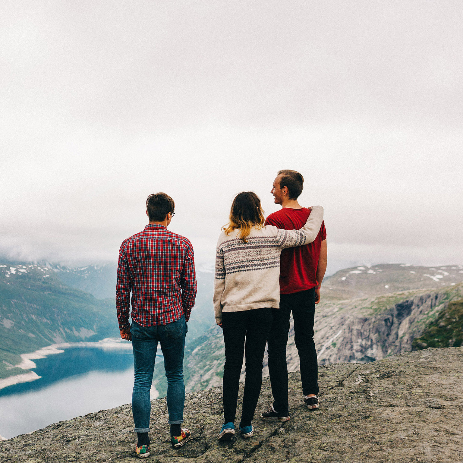 Three young adults standing on the edge of the Trolltunga rock
