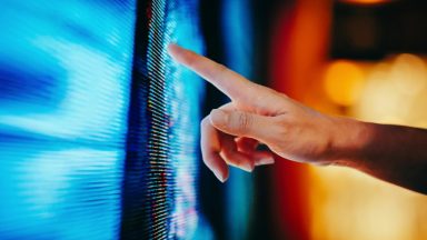 Close up of woman's hand touching illuminated and multi-coloured LED display screen