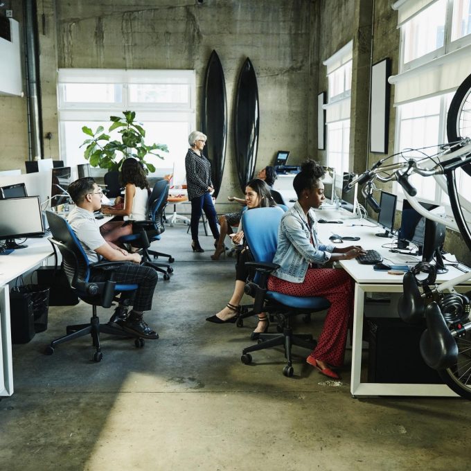 Un grupo de personas que trabajan en un espacio de oficina con escritorios y bicicletas en las que están conversando