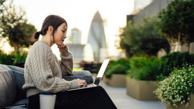 Young businesswoman working on laptop outdoors