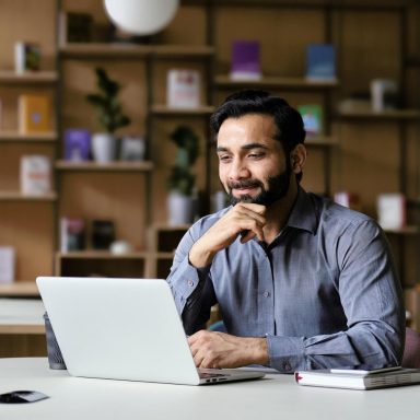 Smiling bearded businessman working on laptop