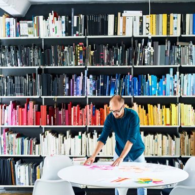 Man working in creative studio in front of colourful bookshelves