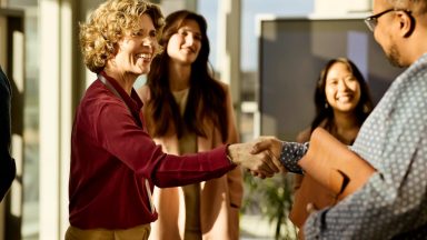 Incontro e stretta di mano in ufficio con persone sorridenti presenti