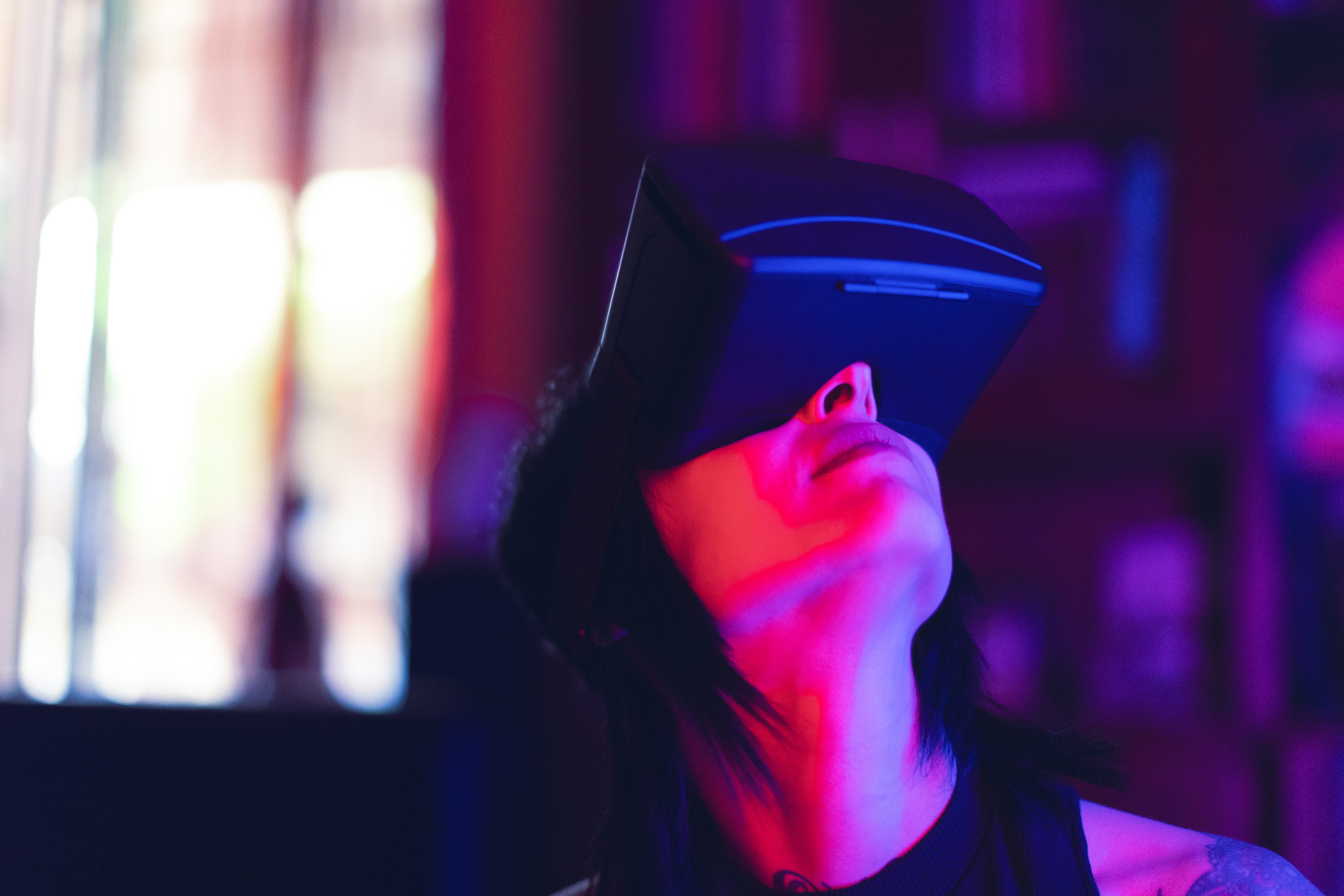 A person is immersed in a virtual reality experience, wearing a headset in a colorful, dimly lit indoor space, capturing the essence of modern technology and gaming culture.