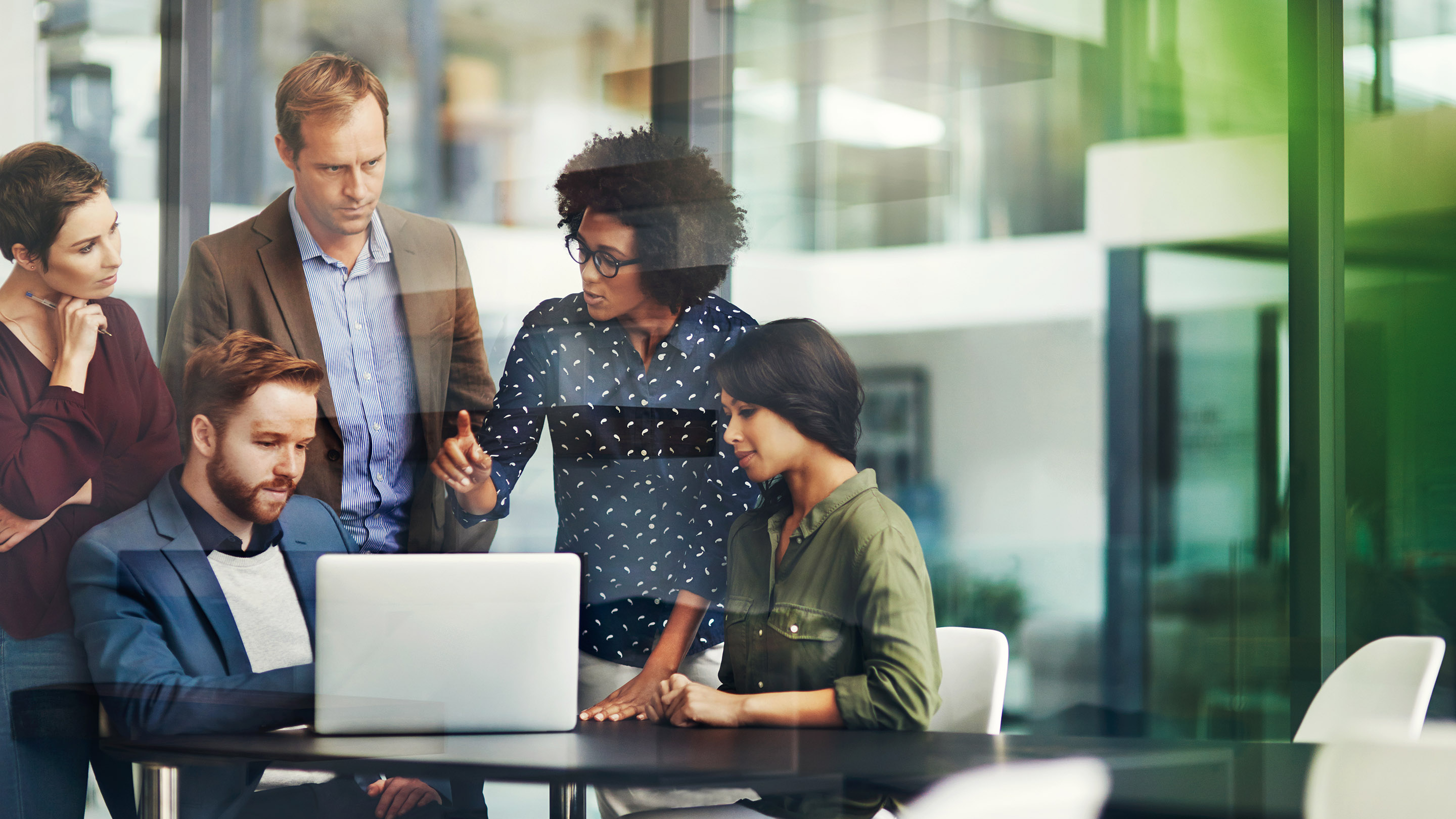 職場でノートパソコンを一緒に使用している同僚のグループのショット