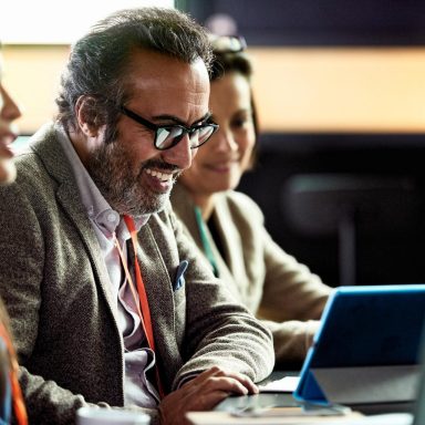 Smiling mature businessman looking at laptop at business meeting