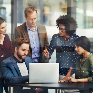 Shot of a group of colleagues using a laptop together at work