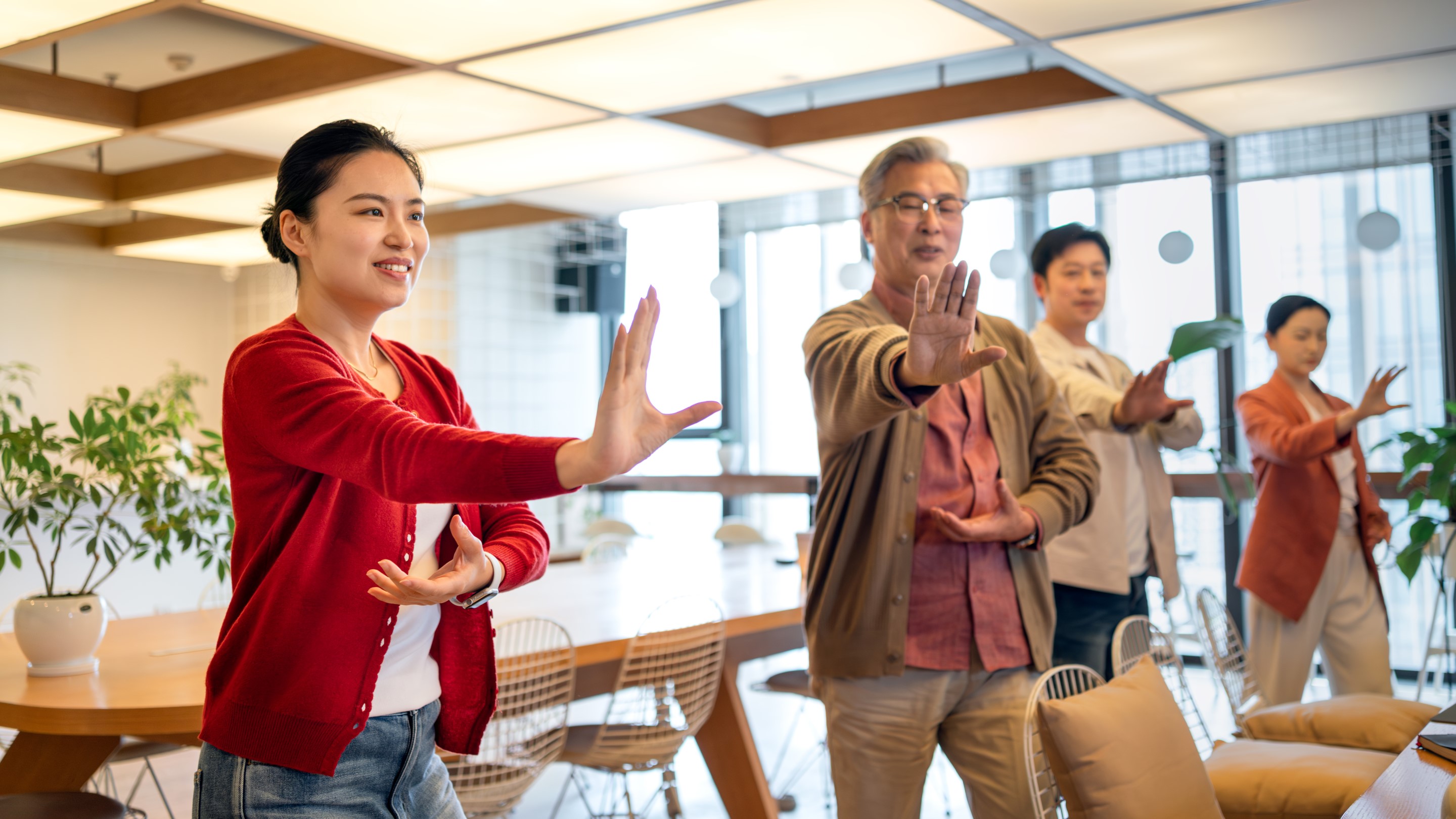 Group of people practicing synchronized gesture or exercise indoors
