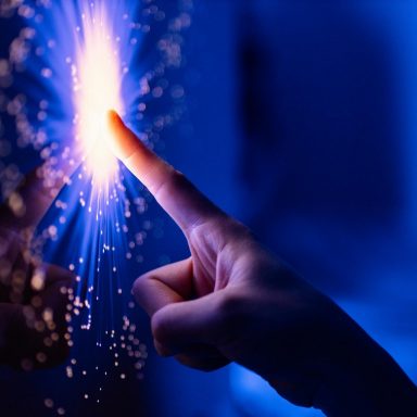 A finger touches a bright light in a dark room