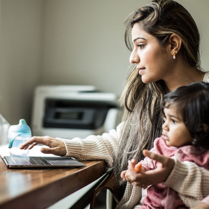 Mother multi-tasking with infant daughter in home office