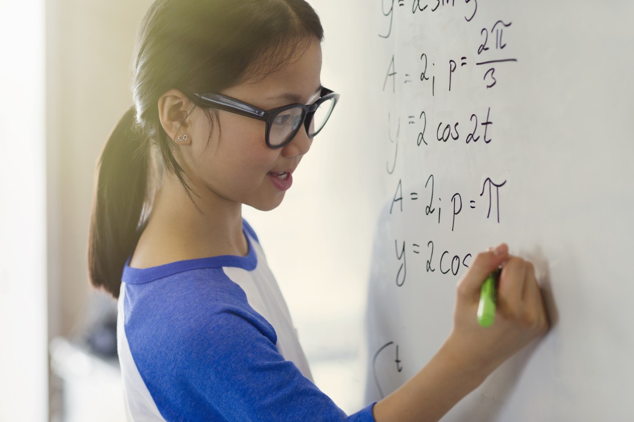 Ein junges Mädchen rechnet an einem Whiteboard