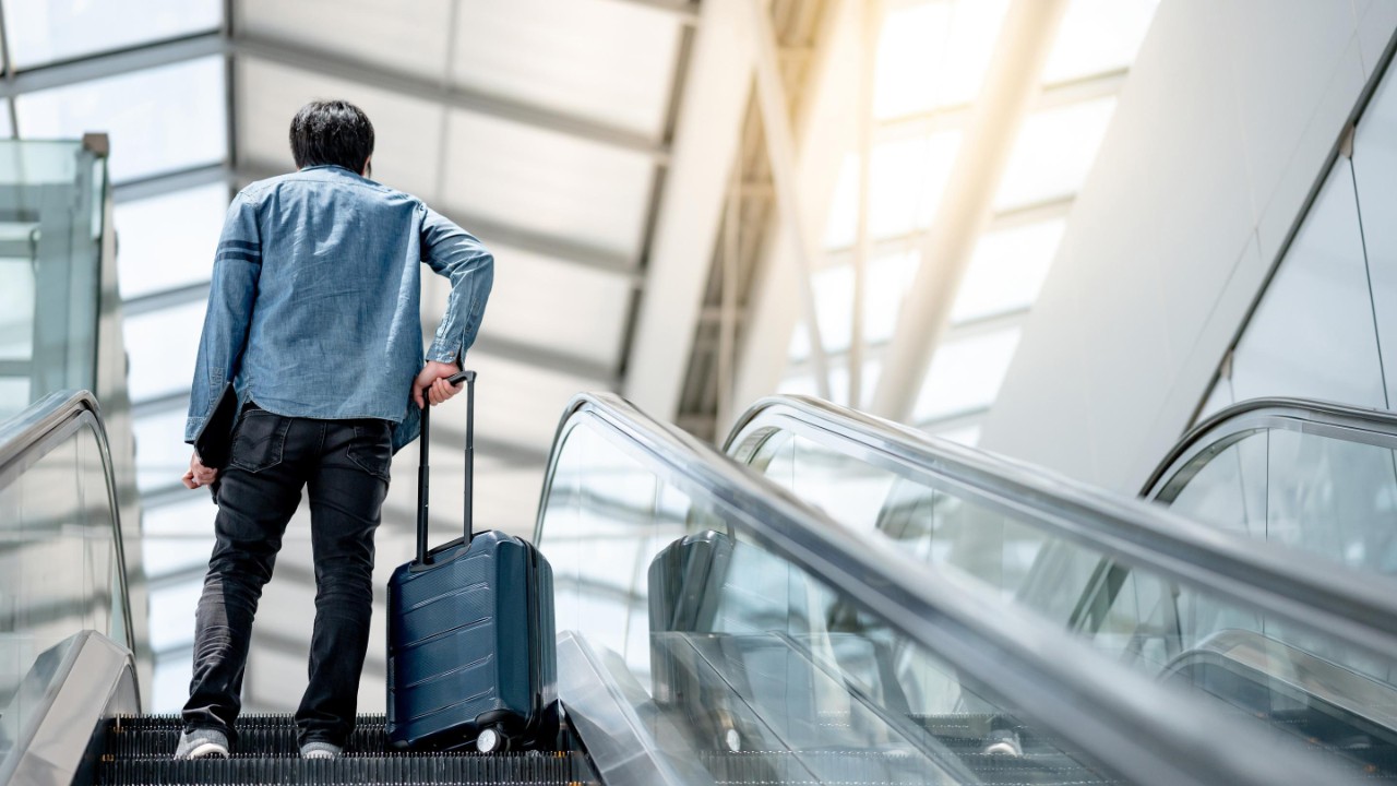 Ein Mann mit Koffer auf einer Rolltreppe