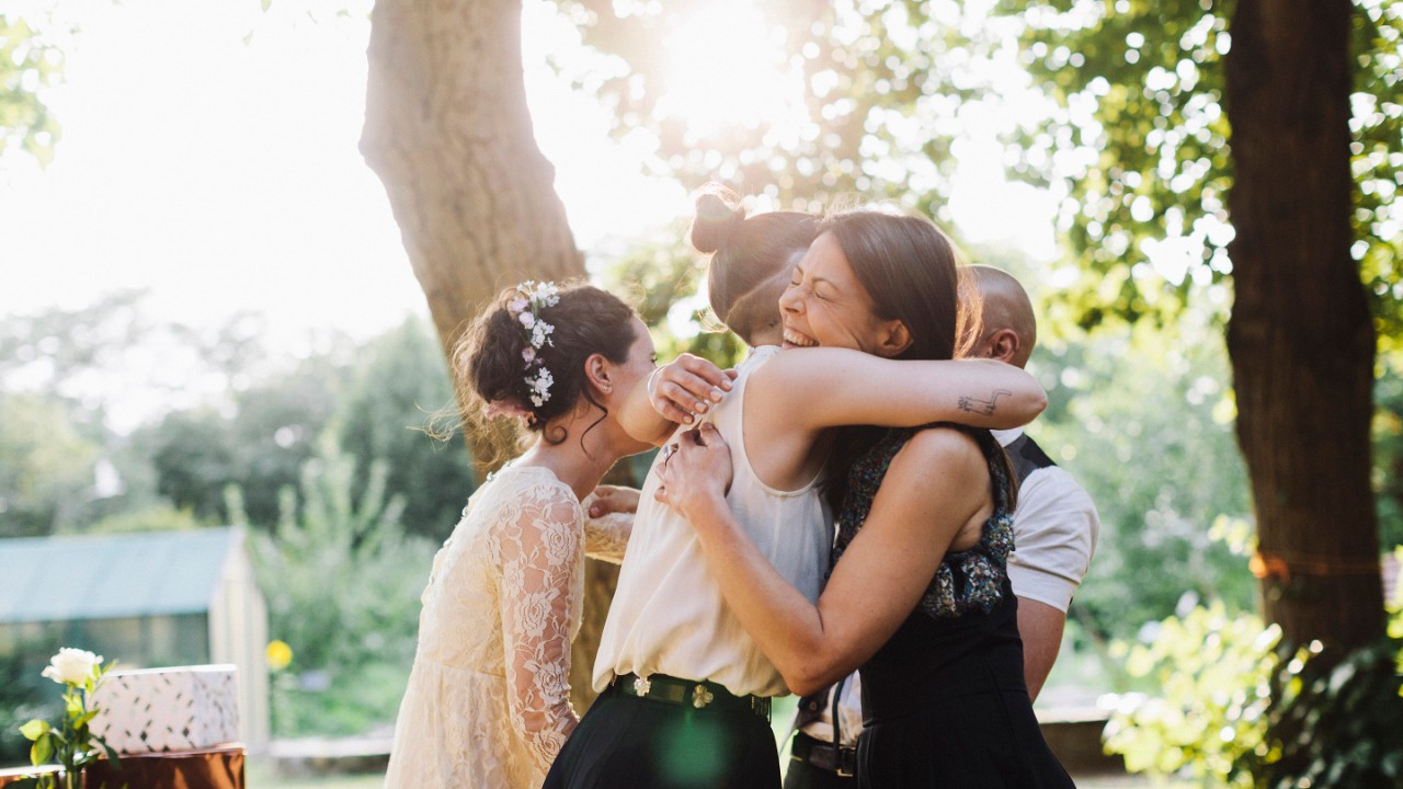 Ein frisch verheiratetes lesbisches Paar wird von einem Hochzeitsgast beglückwünscht