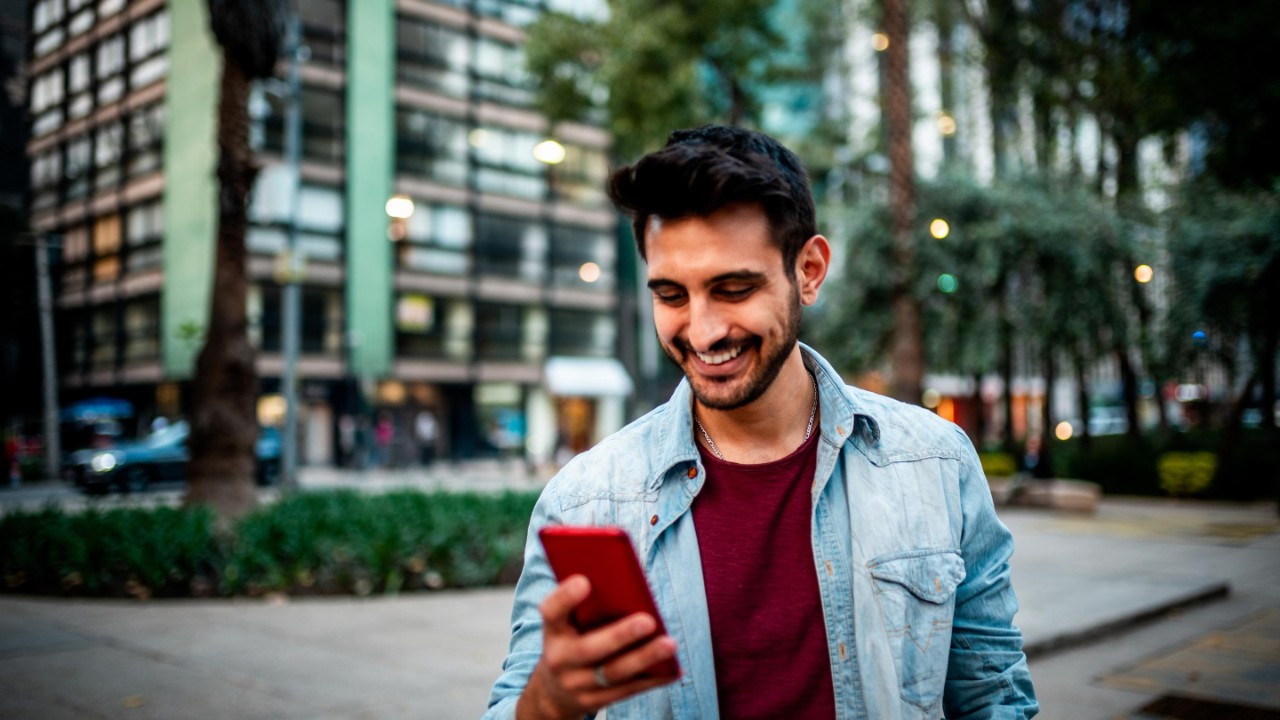 Portrait of a smiling man using mobile phone at the street.