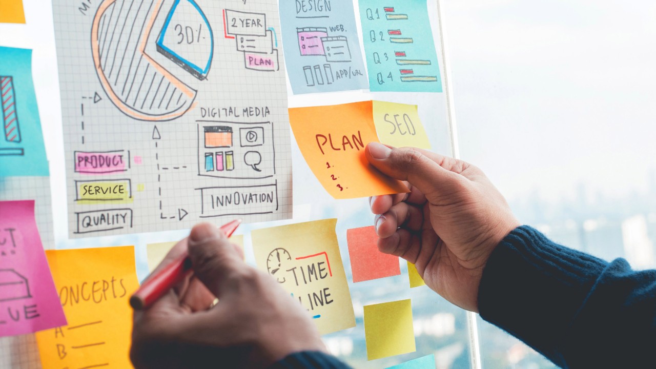 Teilen von Ideenkonzepten mit der Strategie zum Schreiben von Papiernotizen im Wandglasbüro. Geschäftliches Marketing