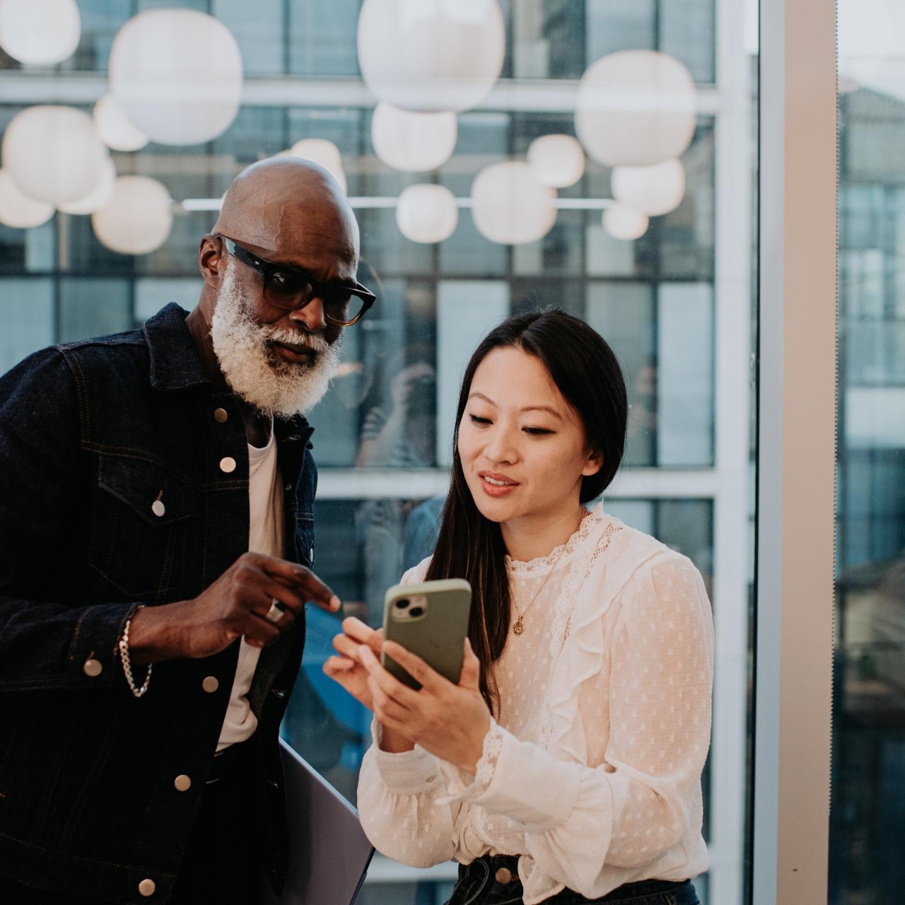 A man and a woman stand in front of a window at dusk