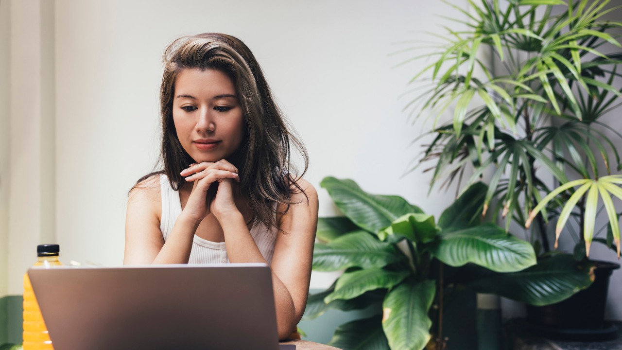 A young Asian woman joining in a video call on her laptop computer.