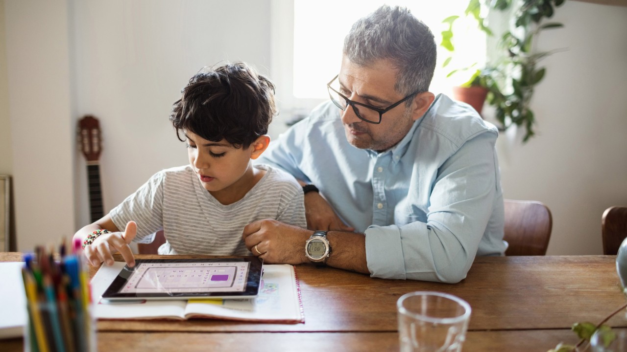 Father assisting son in using digital tablet at home