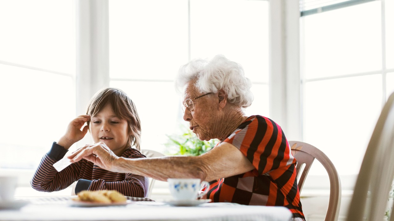 Senior woman showing card to great grandson at home