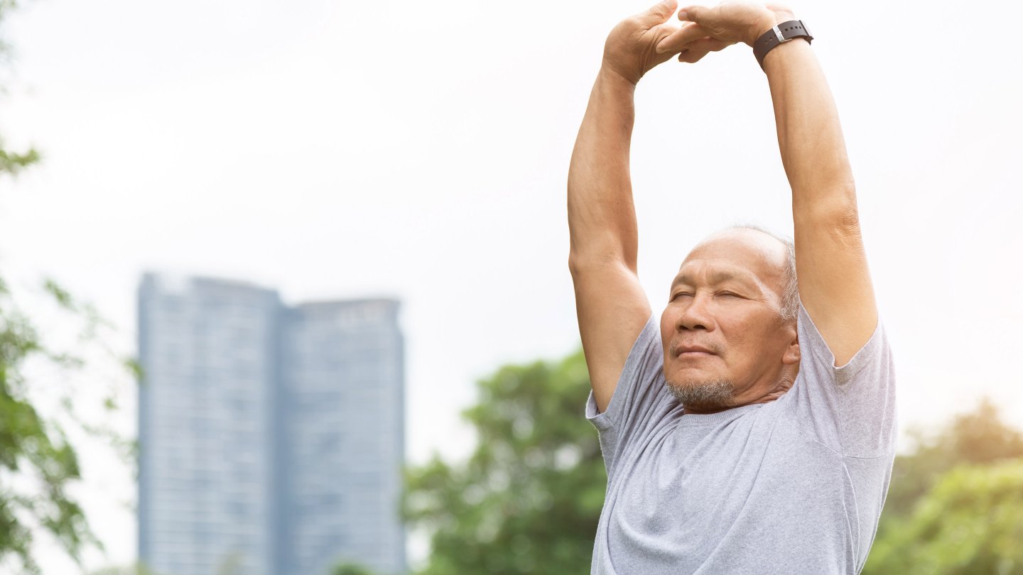 Asian senior man stretching his arms in the air before exercising. Copy space.