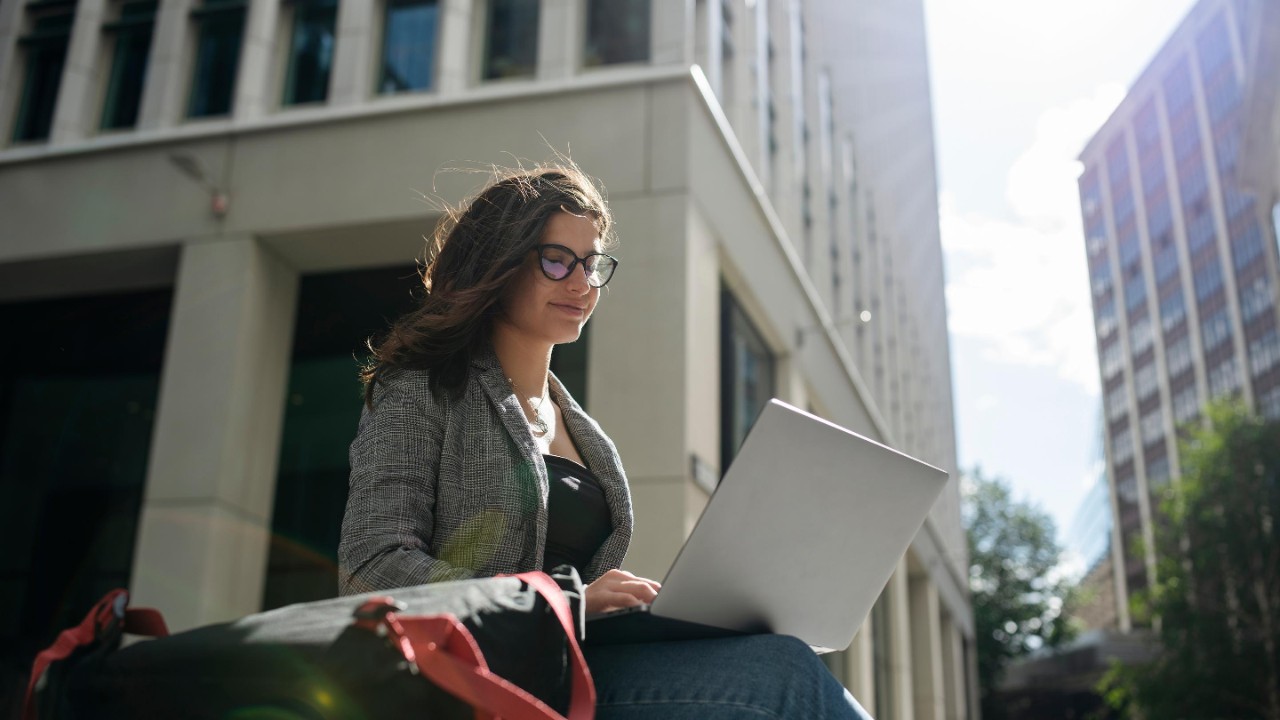 Young businesswoman working with laptop in a business area outdoors.