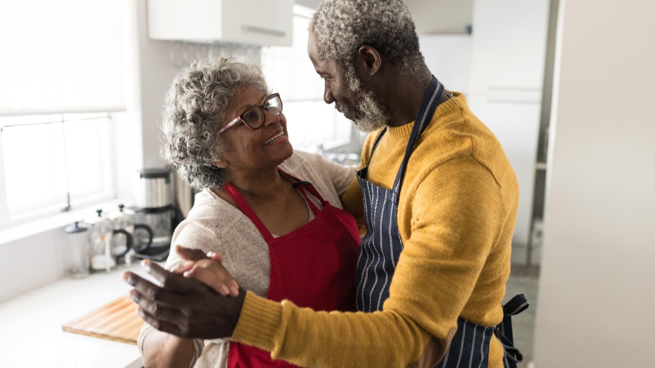 older husband and wife dance in kitchen