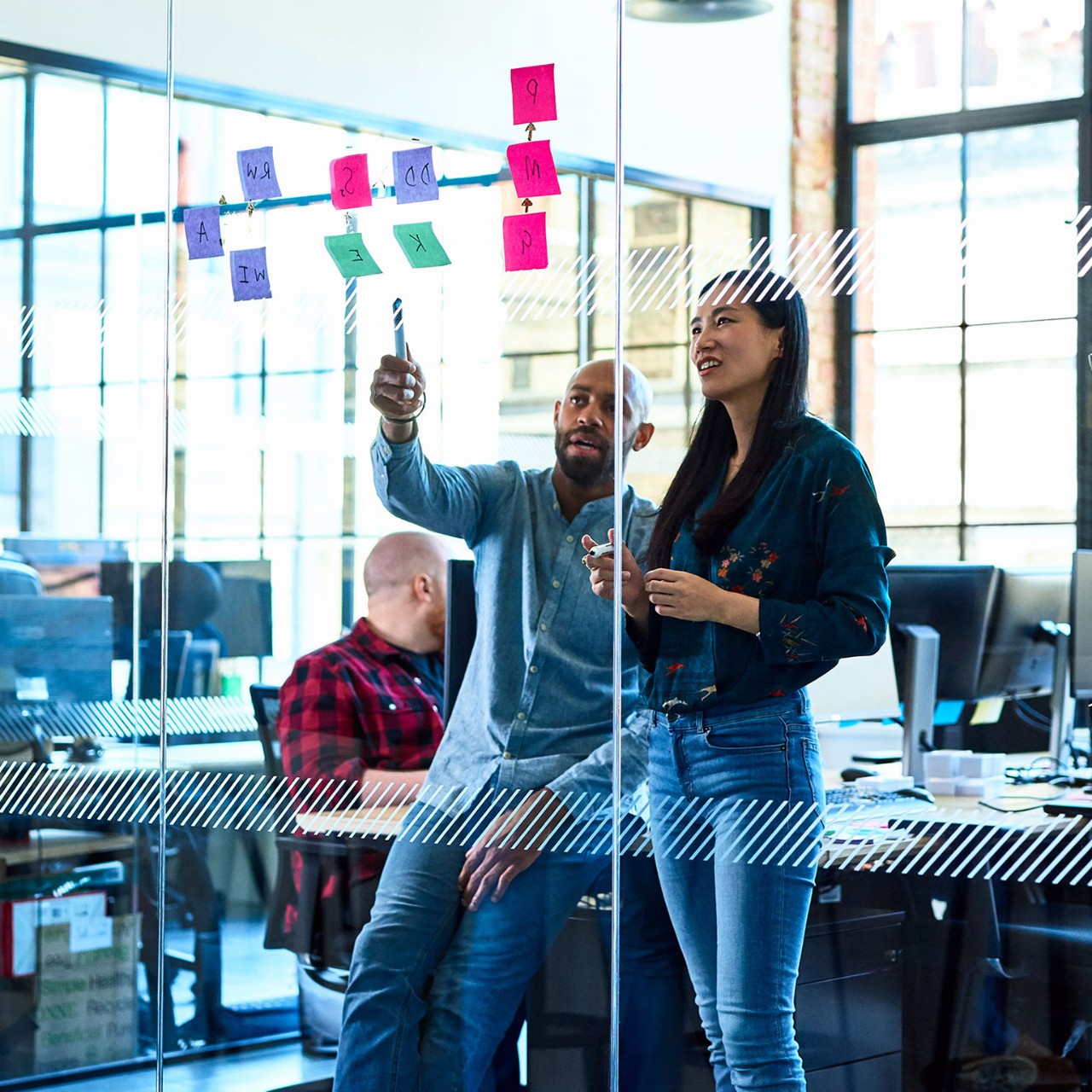 Businessman mentoring female colleague, discussing business strategy, using sticky notes to plan and solve problems, brainstorming, innovation