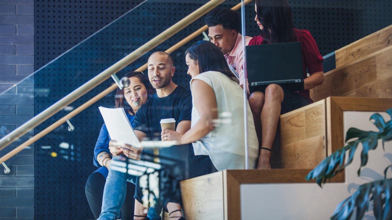 group of colleagues looking at laptop on stairs