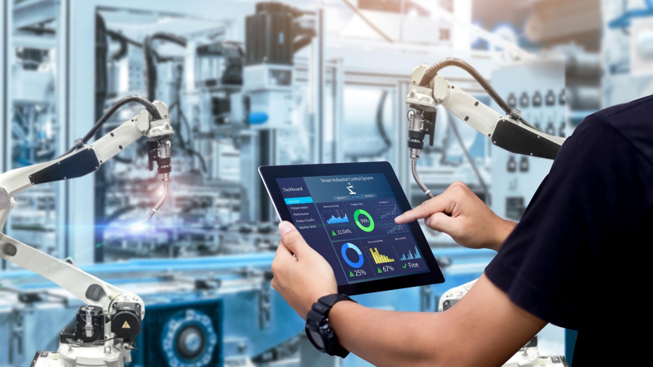 Smart industry control concept.Hands holding tablet on blurred automation machine as background