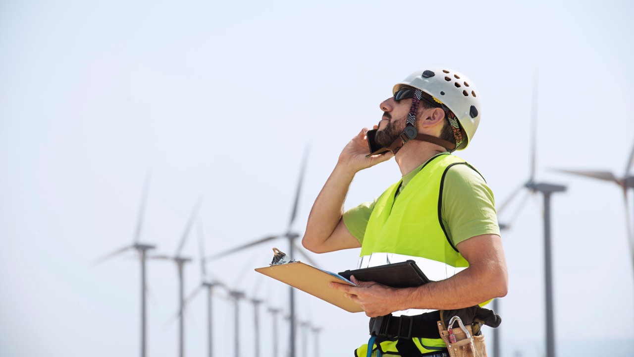 Engineer using smart phone at wind farm