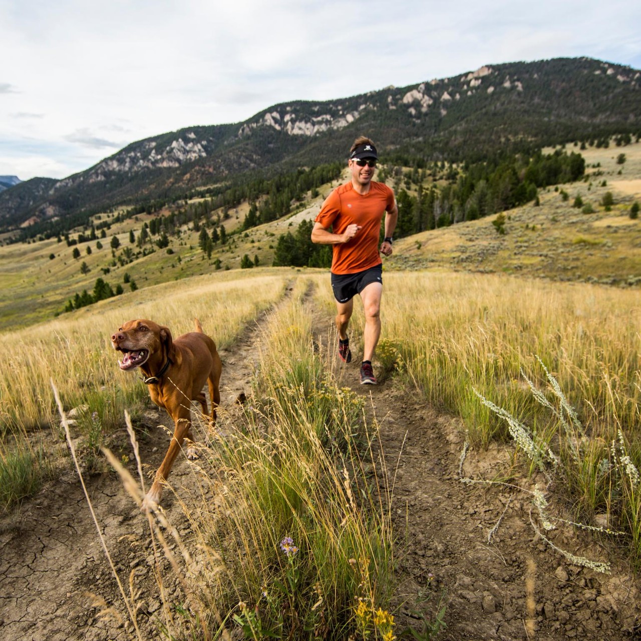 A man Trail running in Big Sky with his dog