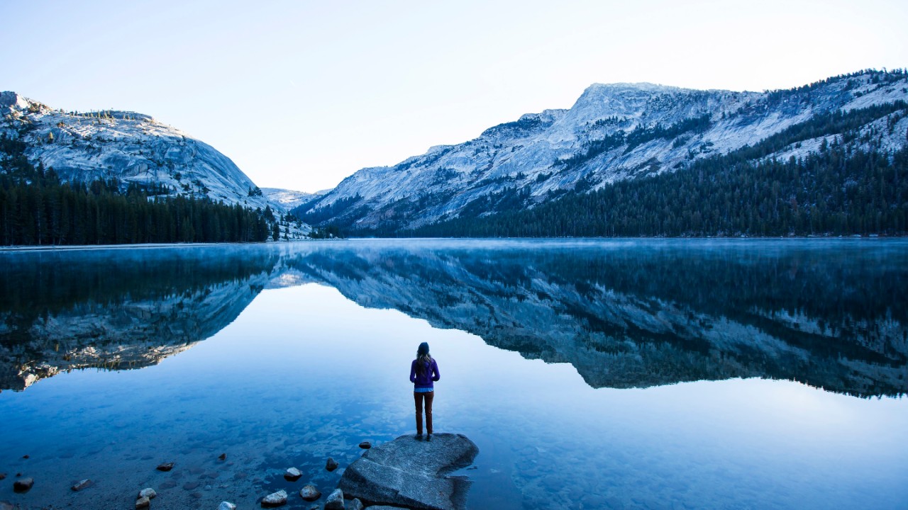 Portrait of confidence Asian businesswoman looking away and holding documents and having coffee to go against city scene in front of modern office buildings