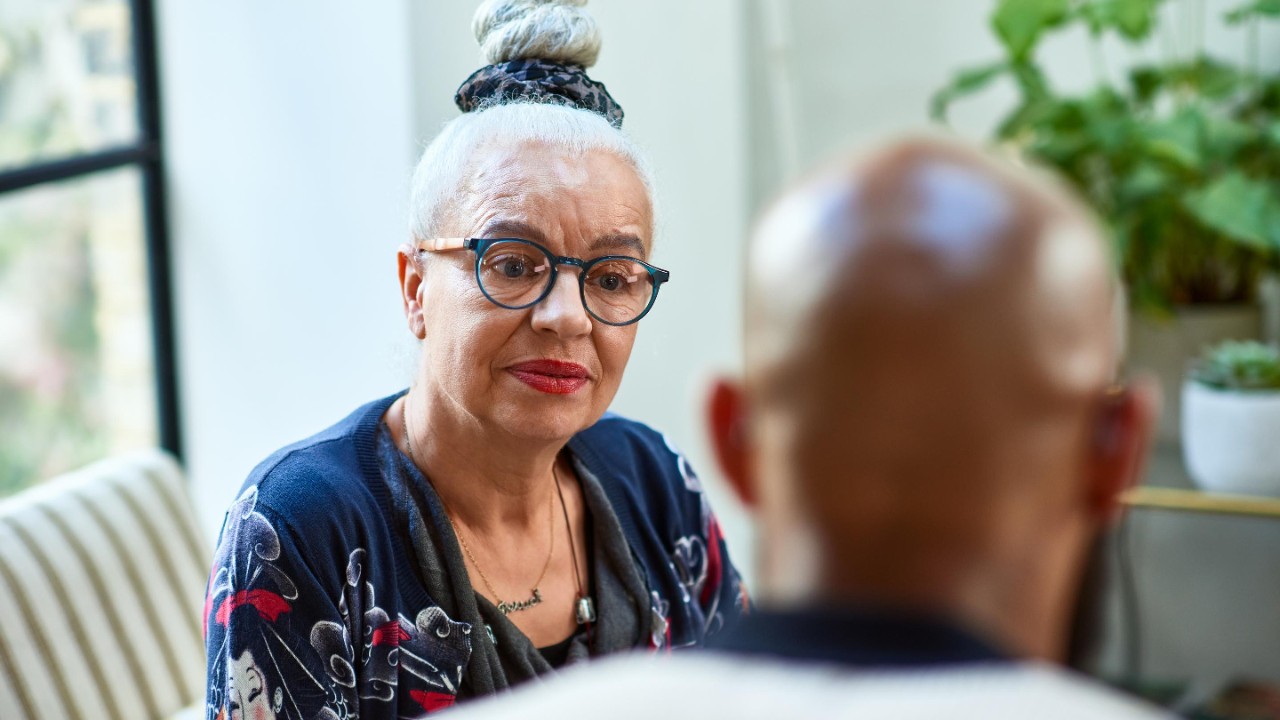 Woman in her 60s wearing glasses looking at man, concentration, care, support