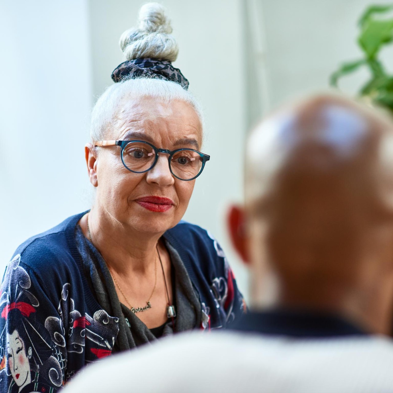 Woman in her 60s wearing glasses looking at man, concentration, care, support