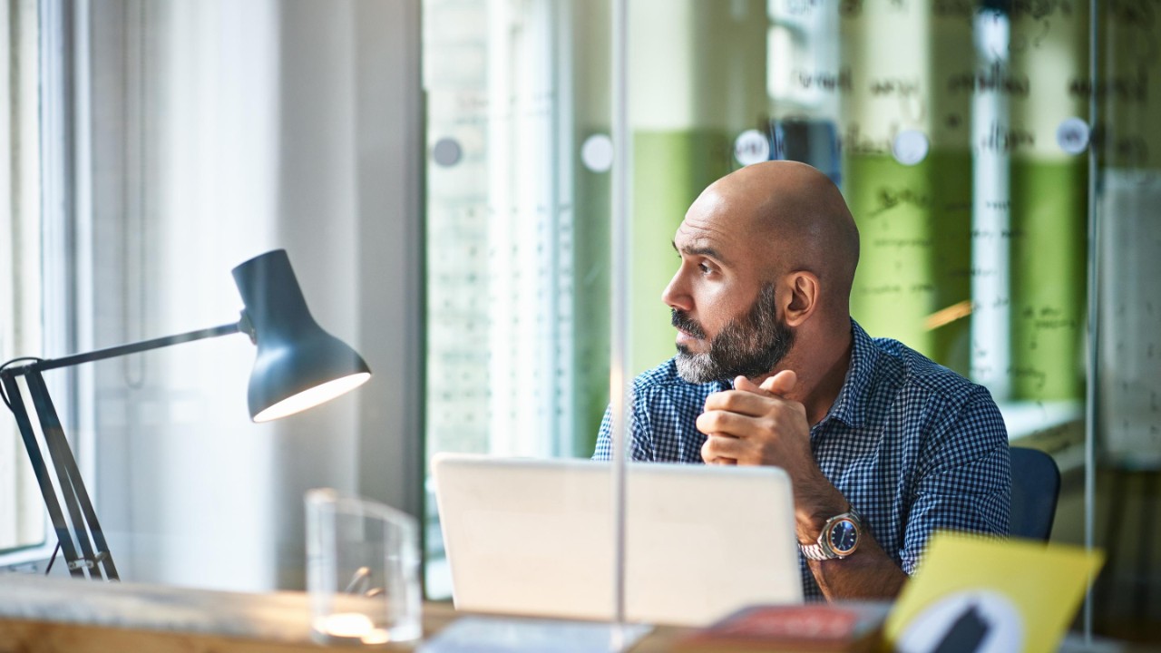 Man on laptop looking outside of window