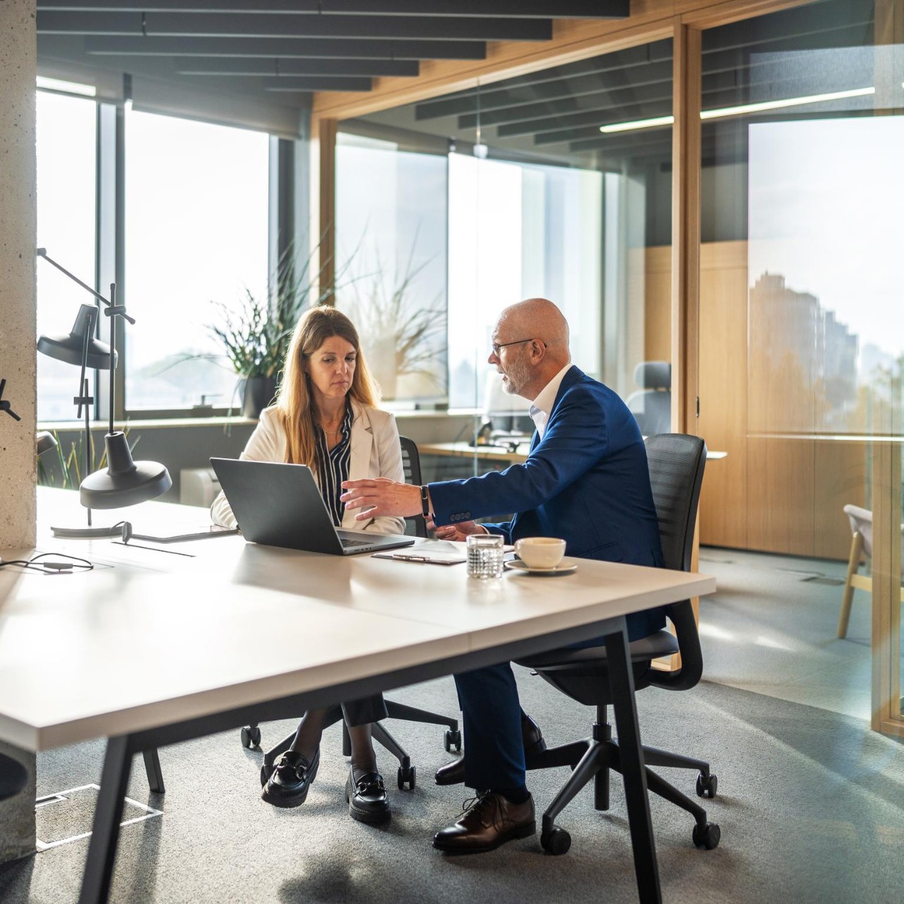 Man and woman work at a laptop in an open plan office