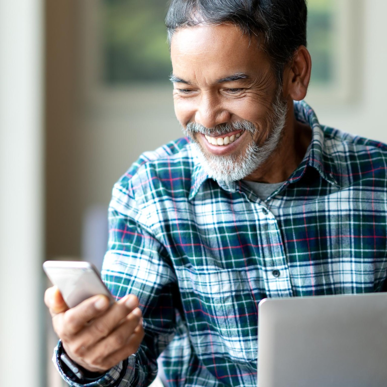senior man uses phone and laptop