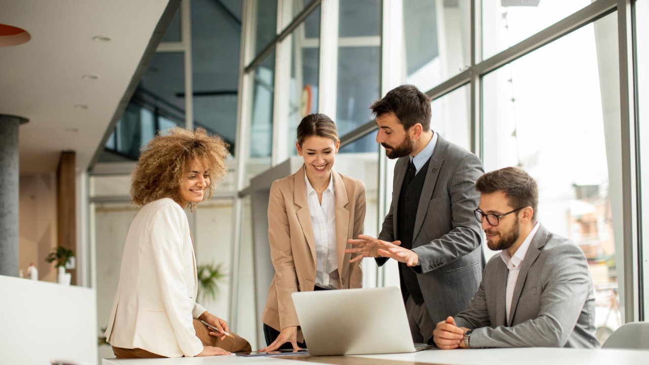 Professional colleagues sitting around a table looking at laptop