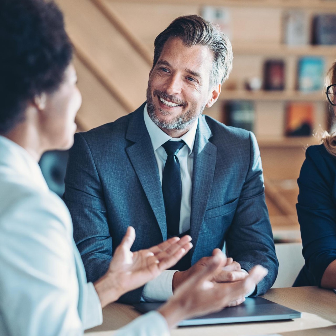 one male and two female colleagues at a table in an office