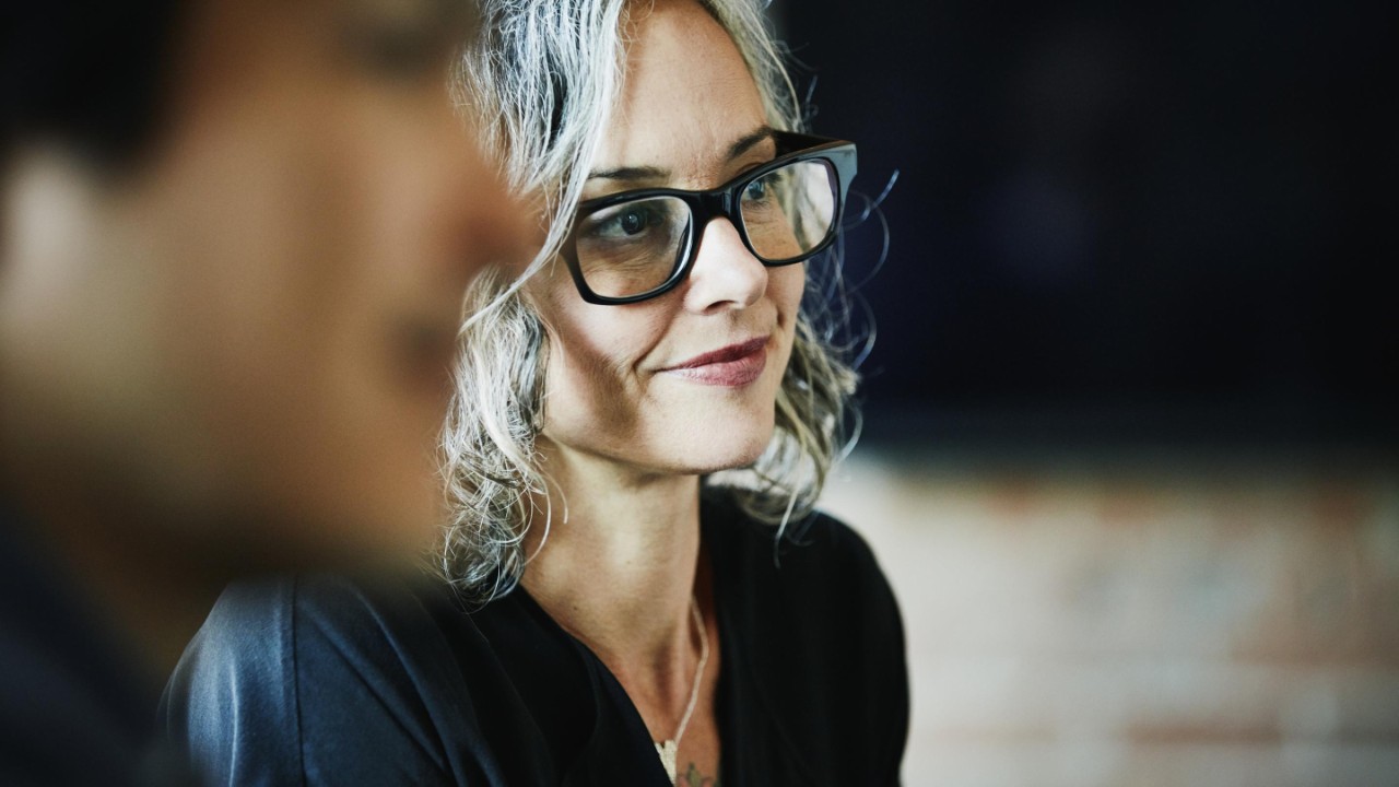 Lady with grey hair, wearing glasses, smiling 