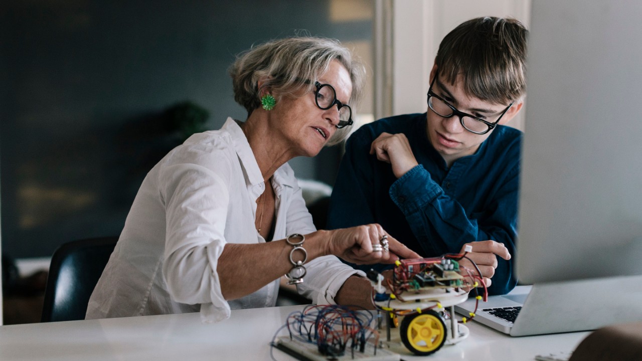 Mother  teaching her teenage son about hobby electronics.