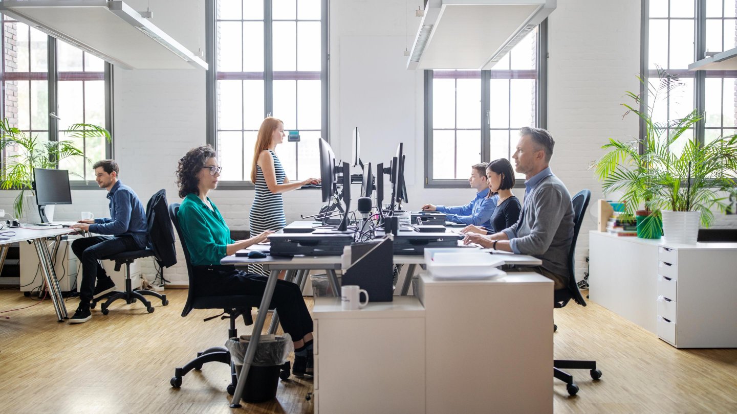  Business people at their desks in a busy, open plan office