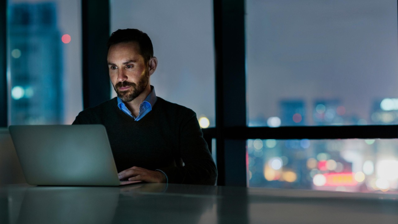 Man viewing laptop computer in office at night