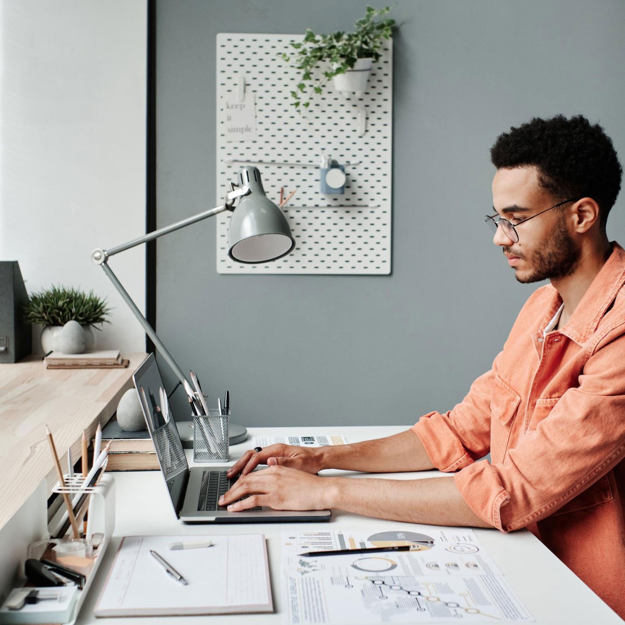 Serious busy young black marketing specialist in eyeglasses working with laptop in minimalistic office