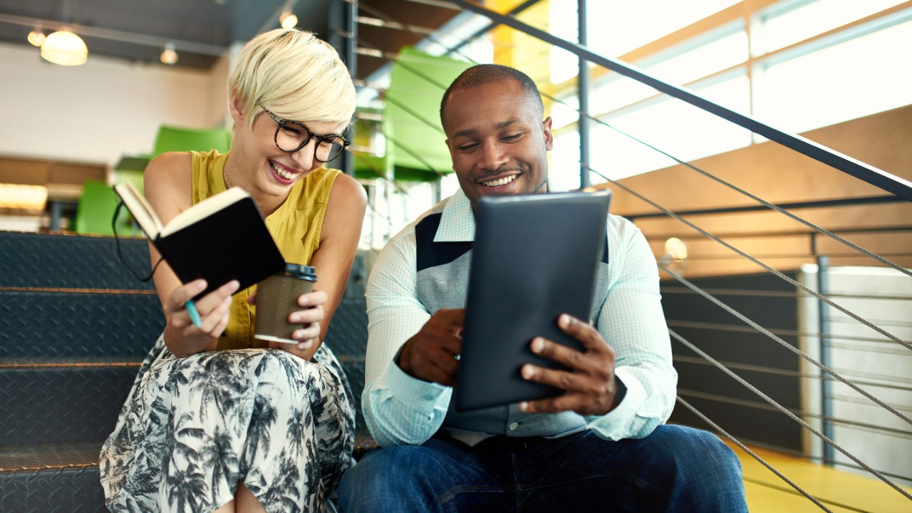 Team of young casual business people collaborating on an online project using a digital touchpad tablet computer in a bright modern office space. Serie with light flares