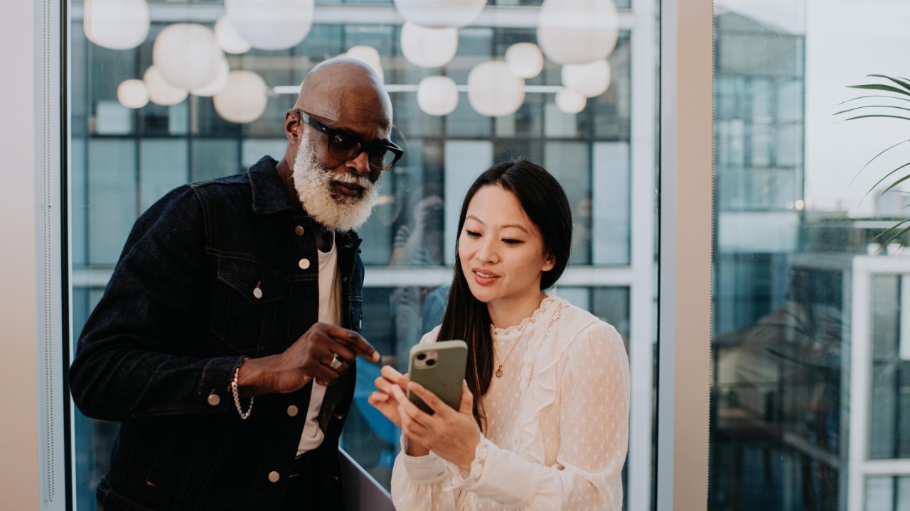 A man and a woman stand in front of a window at dusk