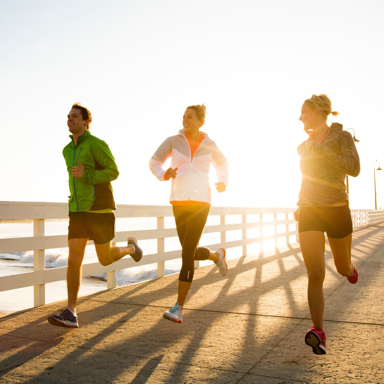 Friends running a boardwalk near the Pacific Ocean