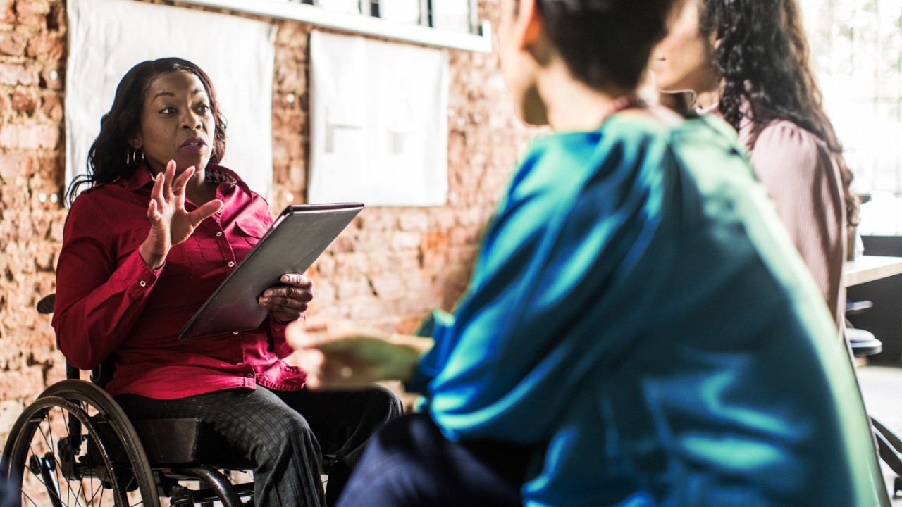 Businesswoman in wheelchair leading group discussion in creative office