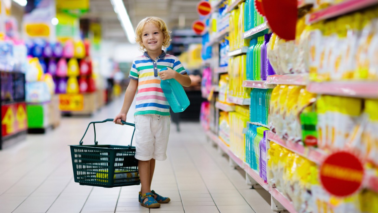 Child in supermarket buying fruit and juice. Kid grocery shopping. Little boy with cart choosing fresh vegetables in local store.