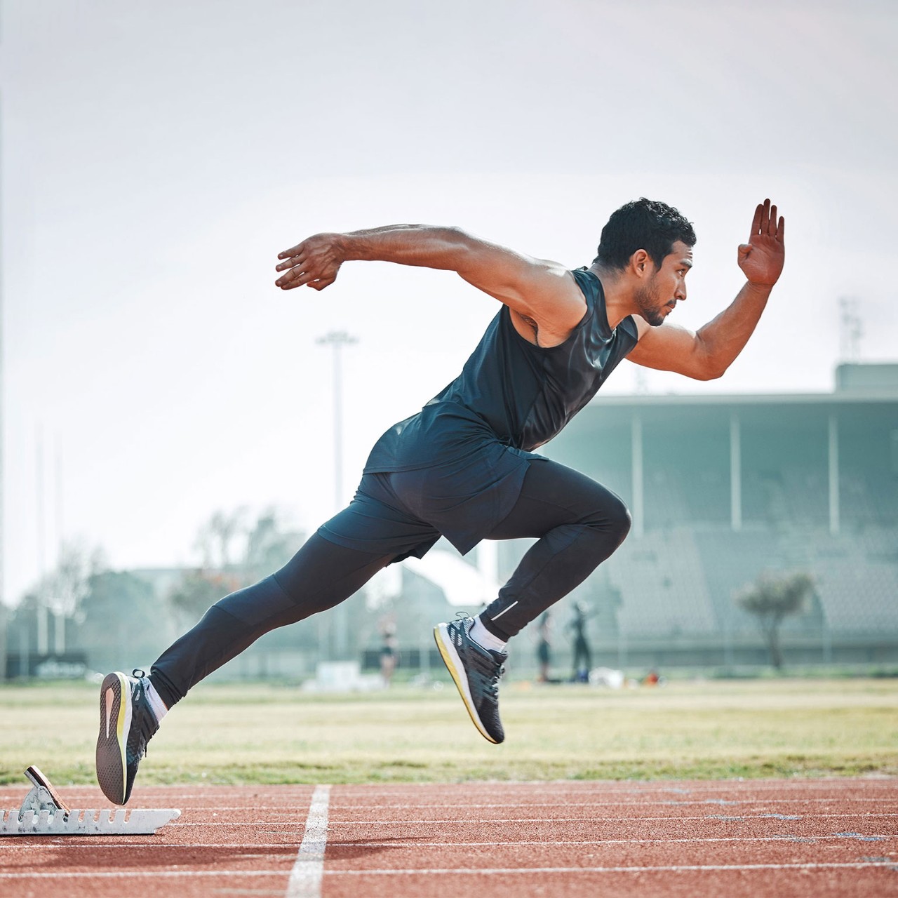 Athletic man running on arena track, sprint race training run and sports